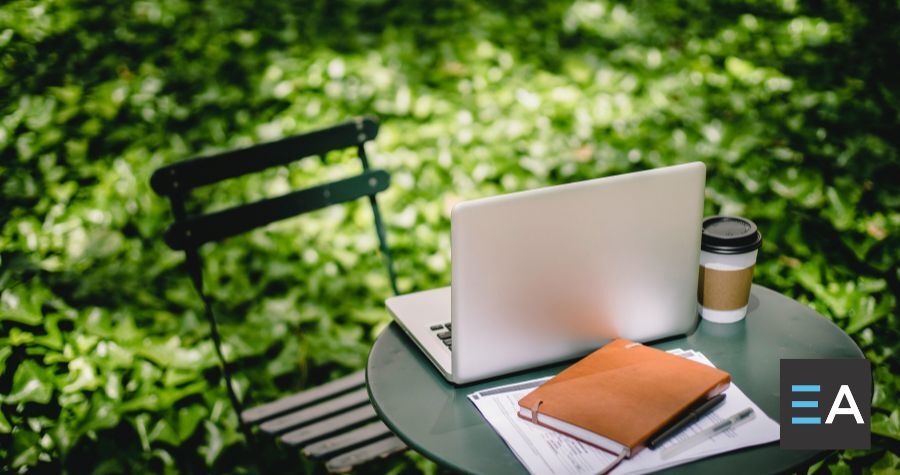 a laptop, book, and coffee set on top of an outdoor table