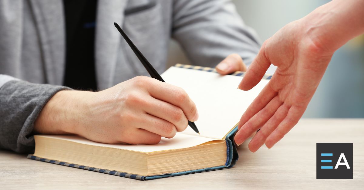 A person autographing a hardcover book