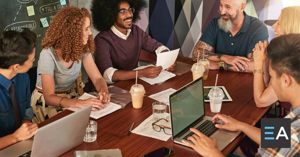 A group of people with laptops and paper at a table