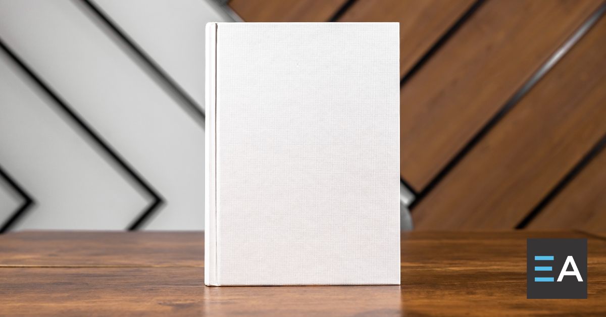 A blank white hardcover book set upright on a wooden table