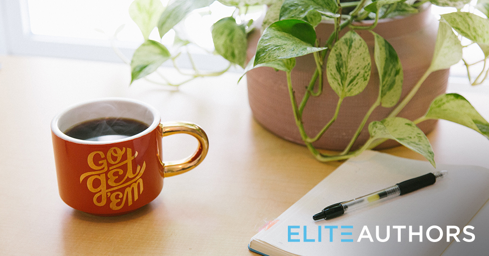 mug next to a plant and pen and paper