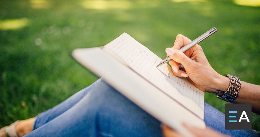 A person writing in a norebook outside