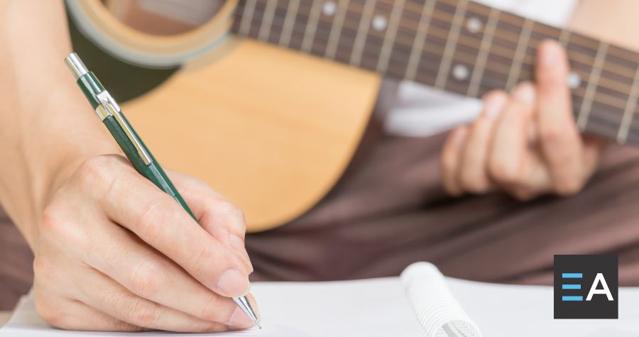 A person with a guitar writing in a notebook