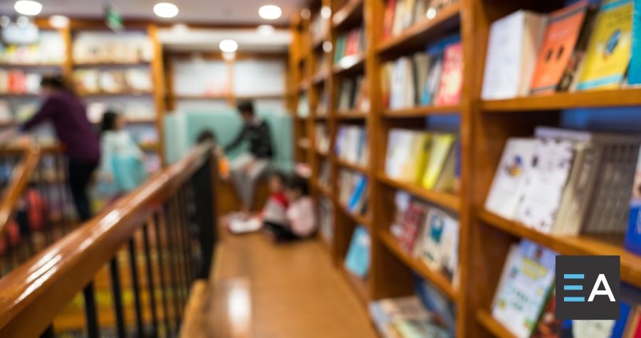 People talking at the end of a long aisle of full bookshelves