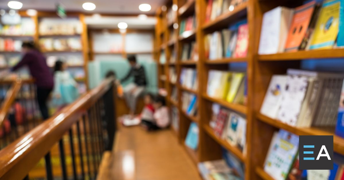 People talking at the end of a long aisle of full bookshelves