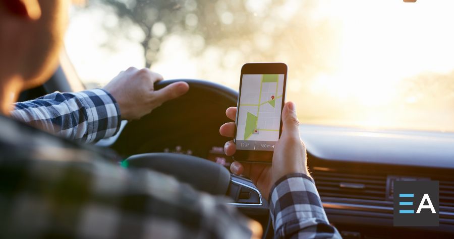 A person behind the wheel of a car looking at a navigation app