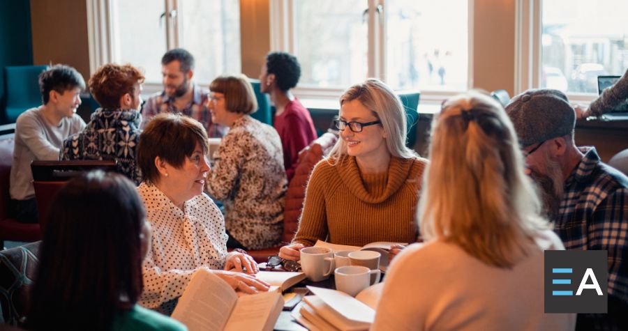 A group of people with books talking around a table