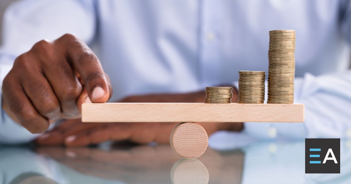 A person balancing a level with their finger on one end and stacks of coins on the other