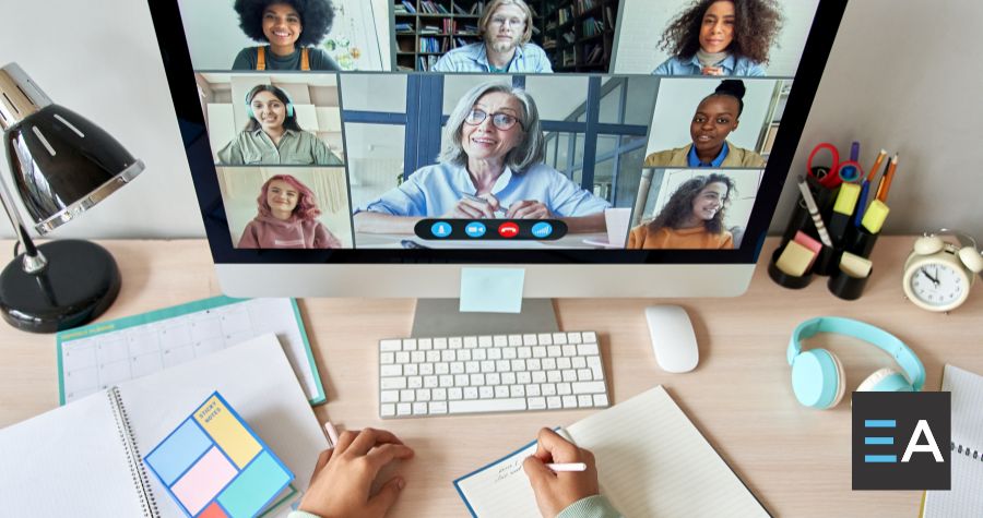 A computer screen displaying a video conference; a person takes notes in front of it