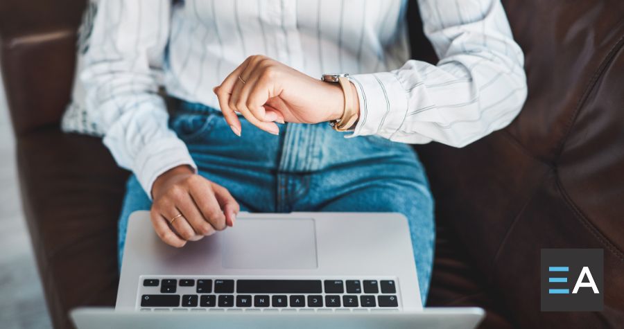 A person with a laptop checking their watch