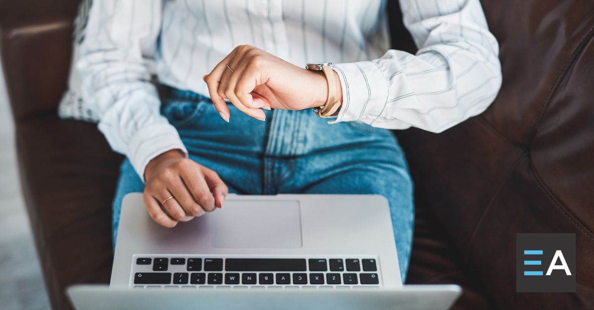 A person with a laptop checking their watch