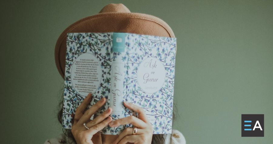 A person whose face is covered by a book