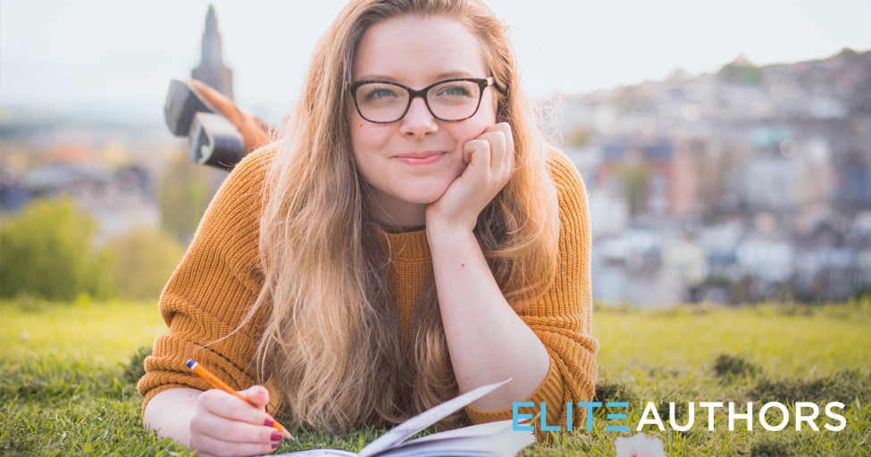 a person laying in the grass with a pen and paper