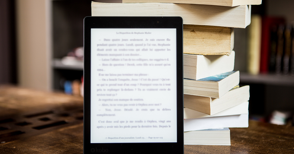 ebook in front of a stack of paperback books