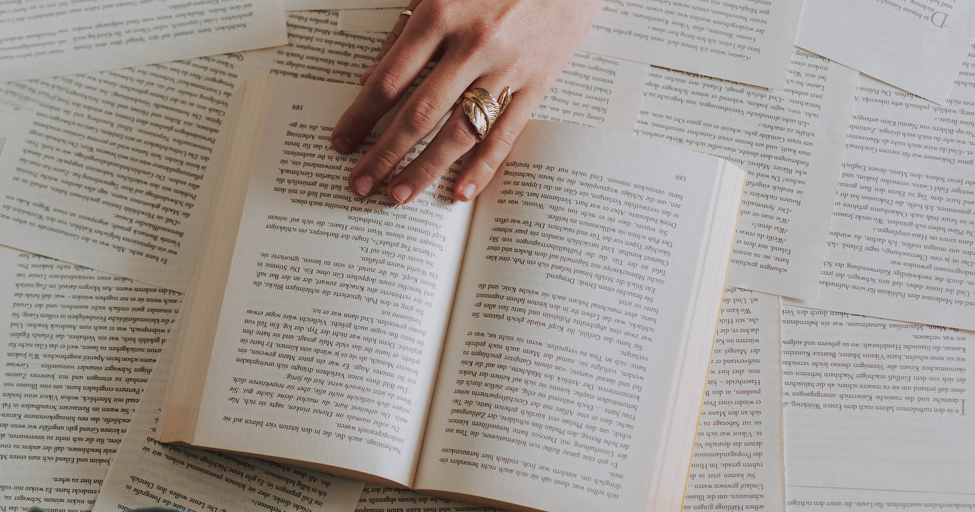 a hand holding a book on top of many loose book pages