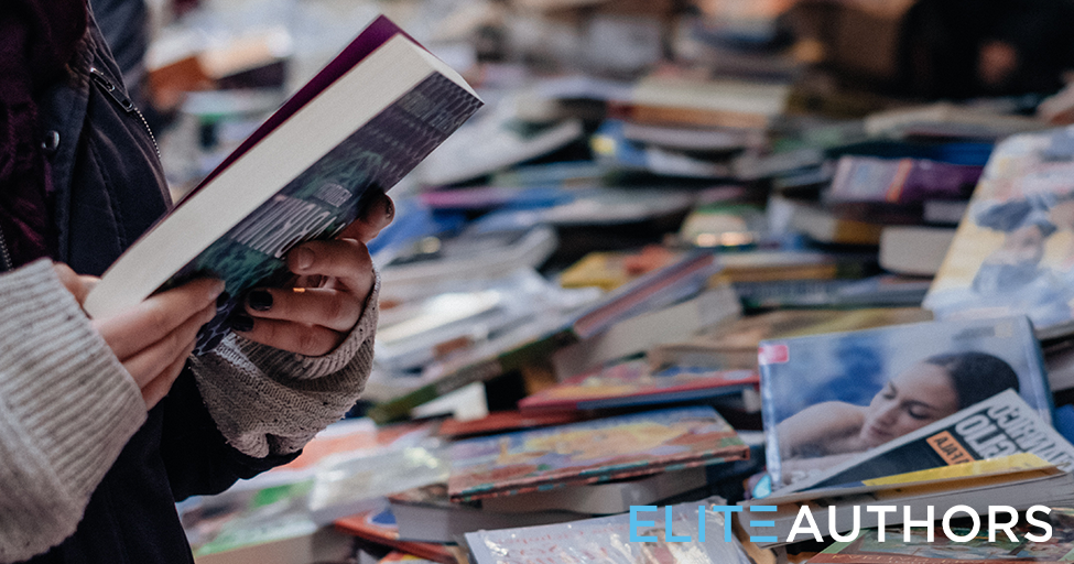 a person looking at a book with a big table of books nearby