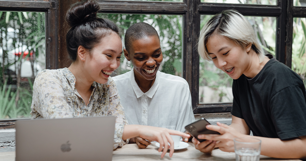 three people laughing at a cell phone